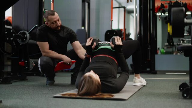 The trainer monitors and helps to perform the buttock reduction exercise correctly. Classes with an experienced coach in a gym with special equipment.