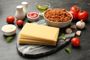 Products for cooking lasagna on dark textured table, closeup