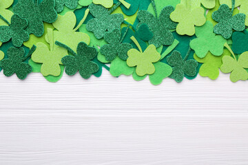 St. Patrick's day. Decorative green clover leaves on white wooden table, flat lay. Space for text