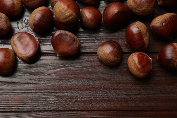 Sweet fresh edible chestnuts on wooden table, top view. Space for text