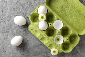 Fototapeta na wymiar Chicken eggs in a green cardboard package with flowers.