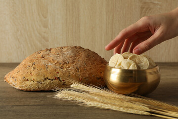 Bread, spikelets and hand on wooden background, close up