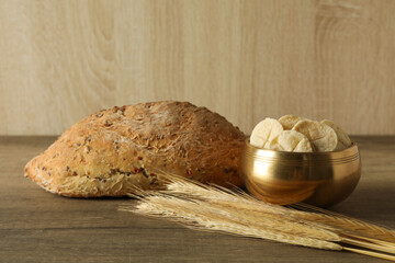 Bread and spikelets on wooden background, close up