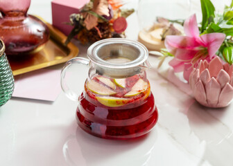 Raspberry tea with apple in a transparent teapot.