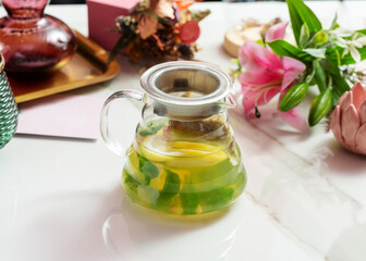 Tea with lemon and mint in a transparent teapot.