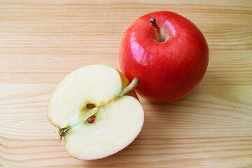 Naklejka na ściany i meble Fresh ripe half cut red apple with whole fruit on wooden background
