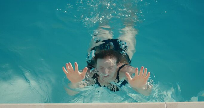 Woman swim under out of water at pool edge summer vacation close up