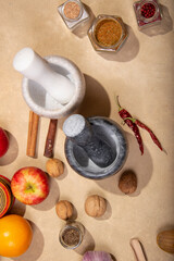 Marble mortars for grinding spices among spices and products on a beige background