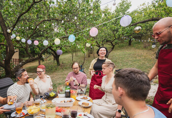 Happy young adult friends having fun enjoying barbecue party in the summer garden