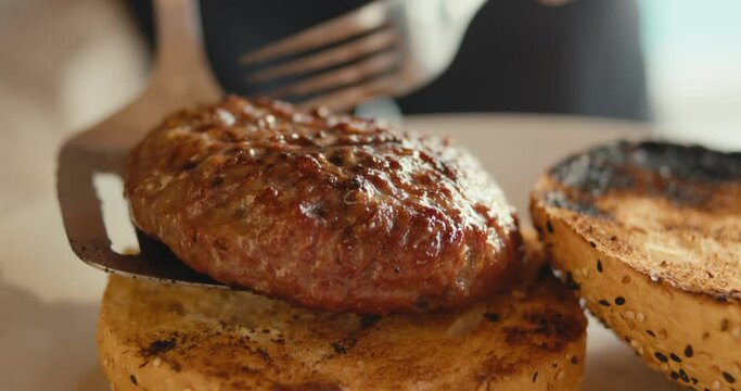 Burger meat put on buns bread on plate spatula fork cooking close up