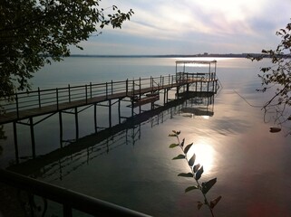Narrow bridge with gazebo for relaxing on pond and sunset on gloomy gray sky