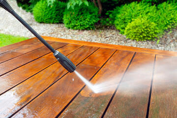 cleaning terrace with a power washer - high water pressure cleaner on wooden terrace surface - shallow depth of field - 740574962