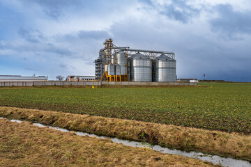 Fototapeta na wymiar agro-industrial complex with silos and a seed cleaning and drying line for grain storage in snow of winter field