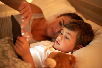 Mother, boy and tablet in bed at night for care, bonding or to watch movies together in family...