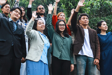 Happy colleagues raising hands together outside the office.