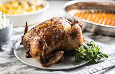 A whole roasted chicken on the table together with jasmine rice and baked potatoes.