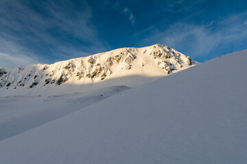 The slope of the ridge illuminated by the first rays of the rising sun. Winter scenery in the morning. - 740592312