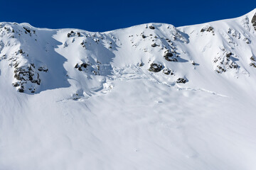 A crack on a steep snow slope in the mountains, which is the initial stage of the formation of a so-called spring (ground) avalanche. - 740592317