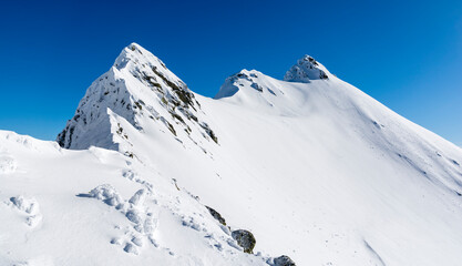 A winter ridge leading to a difficult mountain hiking trail. Tatra Mountains, Poland. - 740592318