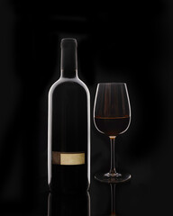 Isolated bottle of red wine and red glass of wine on black background with blank label