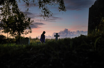 Sunset at the graveyard. Woman standing near cross at cemetry. Dorset England UK.