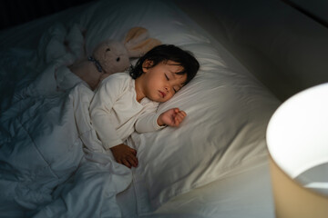 toddler baby sleeping with teddy bear on bed at night