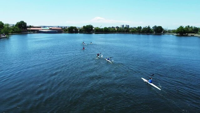 Athletes compete in single boat rowing competitions on Erevan's lake in Armenia. Kayaks sail gracefully across the tranquil waters.