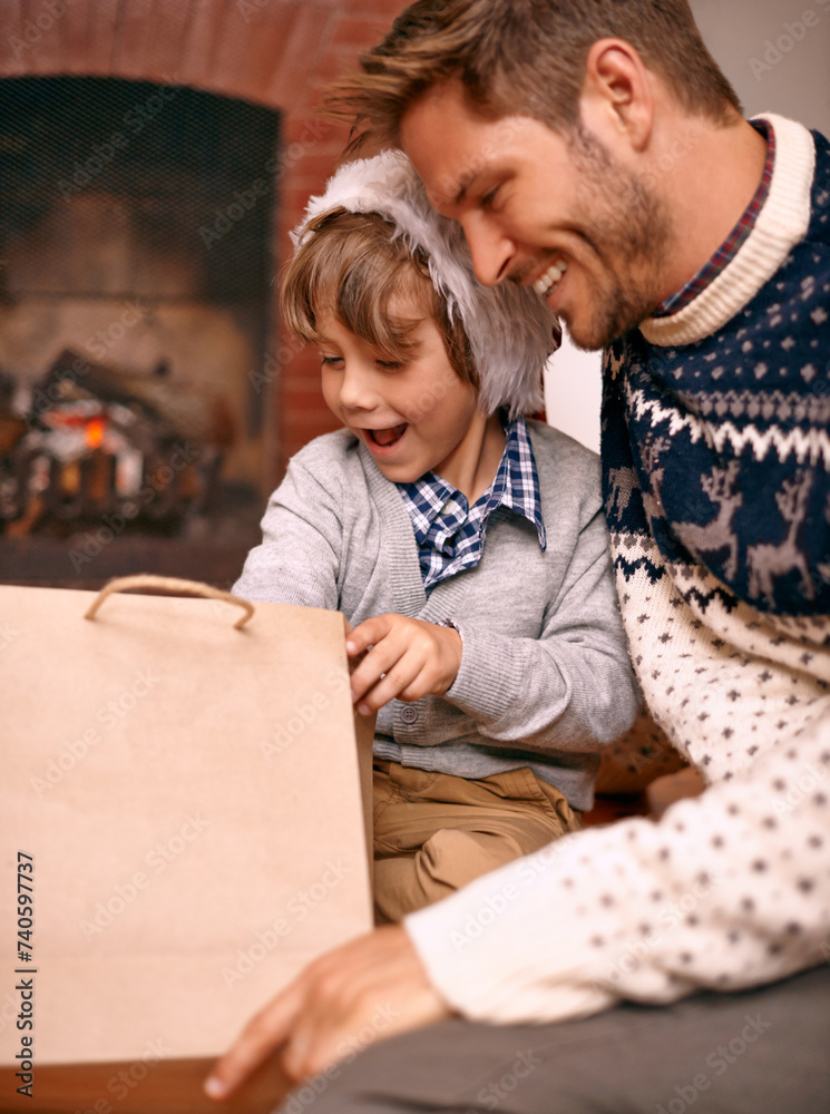 Wall mural Father, son and opening gift on Christmas, curiosity and happy for celebrating a festive holiday. Daddy, child and bonding on religious vacation in living room, childhood and tradition of present