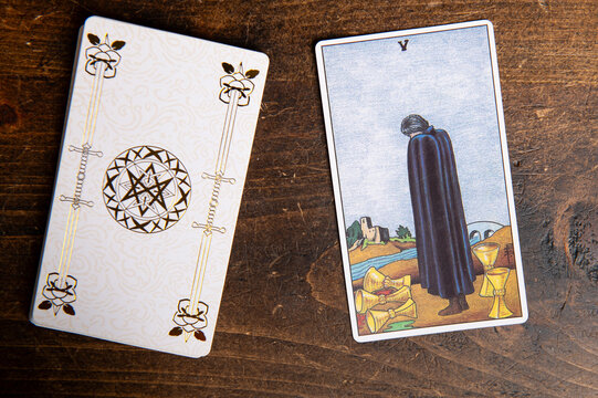 London, UK: 4 January, 2024: Minor Arcana - Five of Cups of Tarot Card of Rider Waite deck on wooden background
