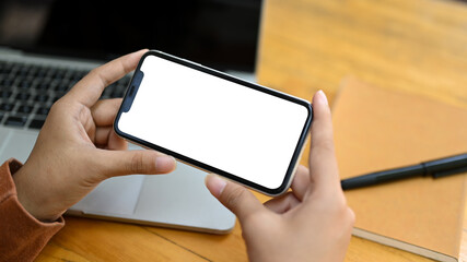 Young woman watching videos or playing video games on smartphone at wooden desk