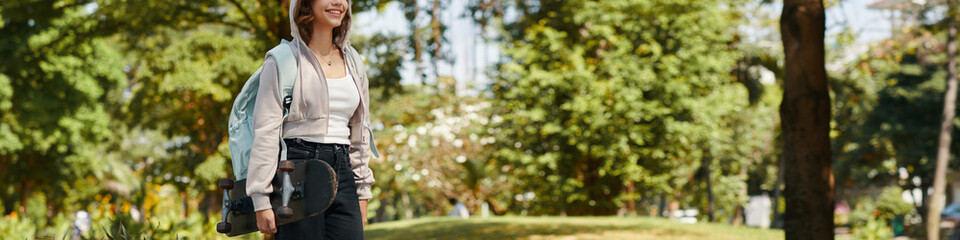 Header with smiling teenage girl with skateboard walking in park