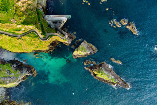 Dunquin or Dun Chaoin pier, Ireland's Sheep Highway. Aerial view of narrow pathway winding down to the pier, ocean coastline, cliffs. Popular location on Slea Head Drive and Wild Atlantic Way.