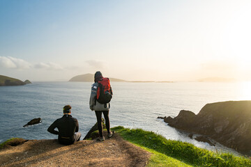 Couple of tourists at Dunquin or Dun Chaoin pier, Ireland's Sheep Highway. Narrow pathway winding...