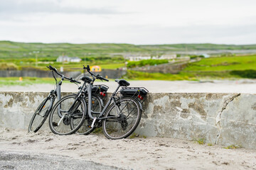 Two electric bikes parked on Inishmore, the largest of the Aran Islands in Galway Bay. Renting a bicycle is one of the most popular way to get around Inis Mor, Ireland. - obrazy, fototapety, plakaty