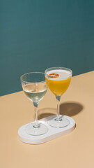 Two glasses with an alcoholic cocktail on a podium on a colored background