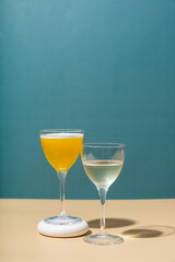 Two glasses with an alcoholic cocktail on a colored background