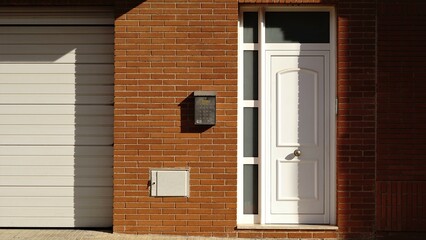 red brick wall house facade with white door and mailbox