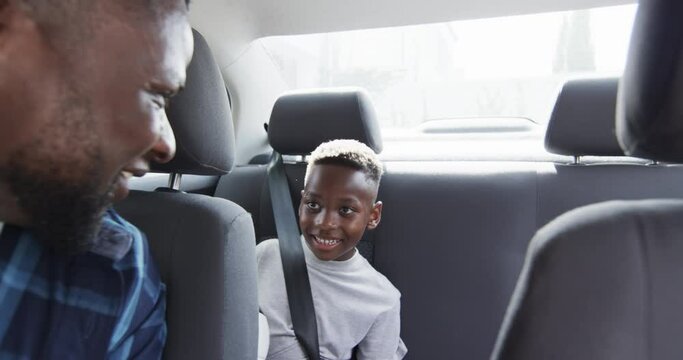 African American father gives high five to son in car, with copy space