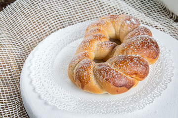 Bun with sugar sprinkles on a white wooden tray