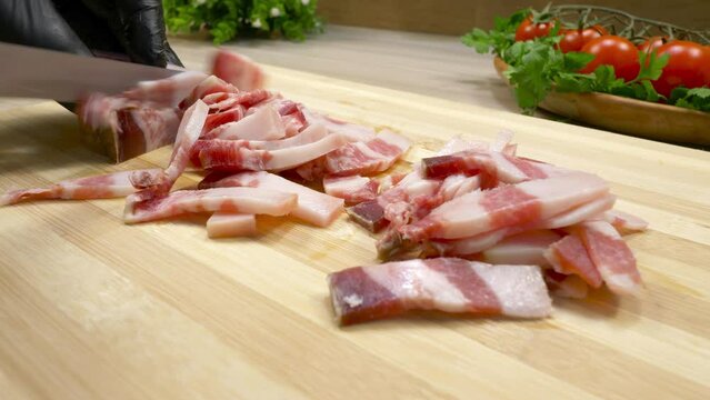 Slicing pork belly with a knife on a cutting board. Cured bacon on a cutting board