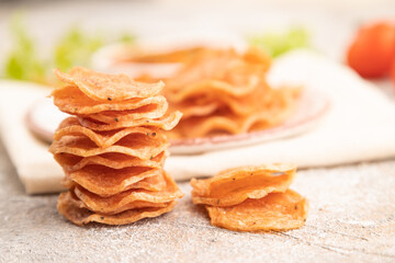 Slices of dehydrated salted meat chips on gray concrete, side view, selective focus