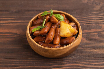 Tteokbokki or Topokki, fried rice cake stick, on brown wooden, side view