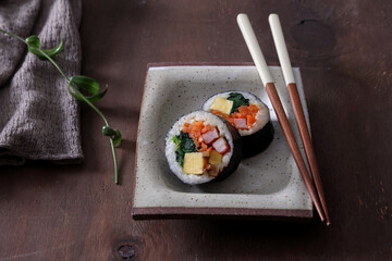 Kimbap with salmon, egg and cheese on wooden background