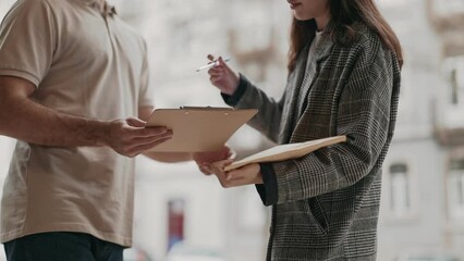 Unrecognizable courier delivering an envelope and asking for confirmation signature from the client outdoors