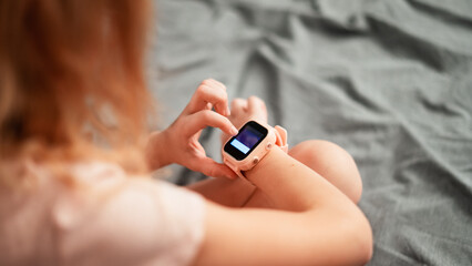 Fototapeta premium A little girl is wearing a smart watch on her wrist