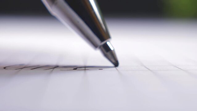 Ballpoint pen writes on a sheet of paper, extreme close-up shot.
