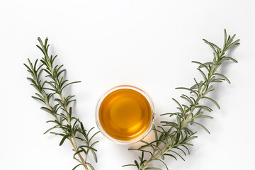 Glass cup of tea and sprigs of fresh rosemary on a white background