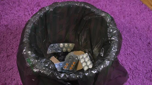 they throw a bunch of different pills into the trash, get rid of medications, medications are no longer needed, packs of antibiotics are thrown away, pills are thrown away