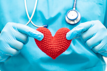 Doctor holding a red heart in hospital ward, healthy strong medical concept.