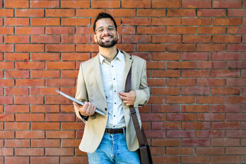 Portrait of young business man outside office building in the alley with brick wall background...